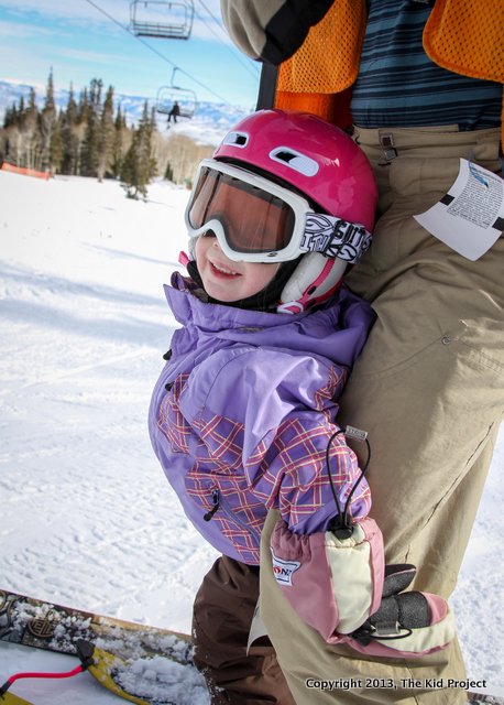 Happy toddler girl skiing with family